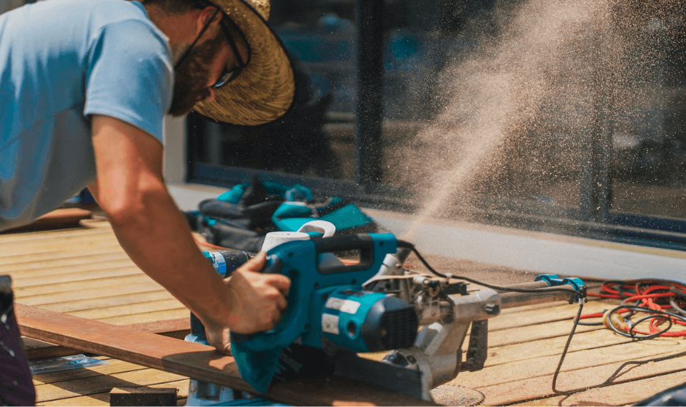 man cutting through a plank